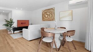 Una sala moderna con una mesa de comedor redonda, un sofá blanco y un piano negro.