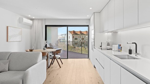 Un apartamento moderno con balcón, zona de comedor y kitchenette.