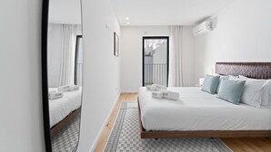 Una habitación de hotel moderna con una cama grande, un cabecero de madera y vistas a un balcón.