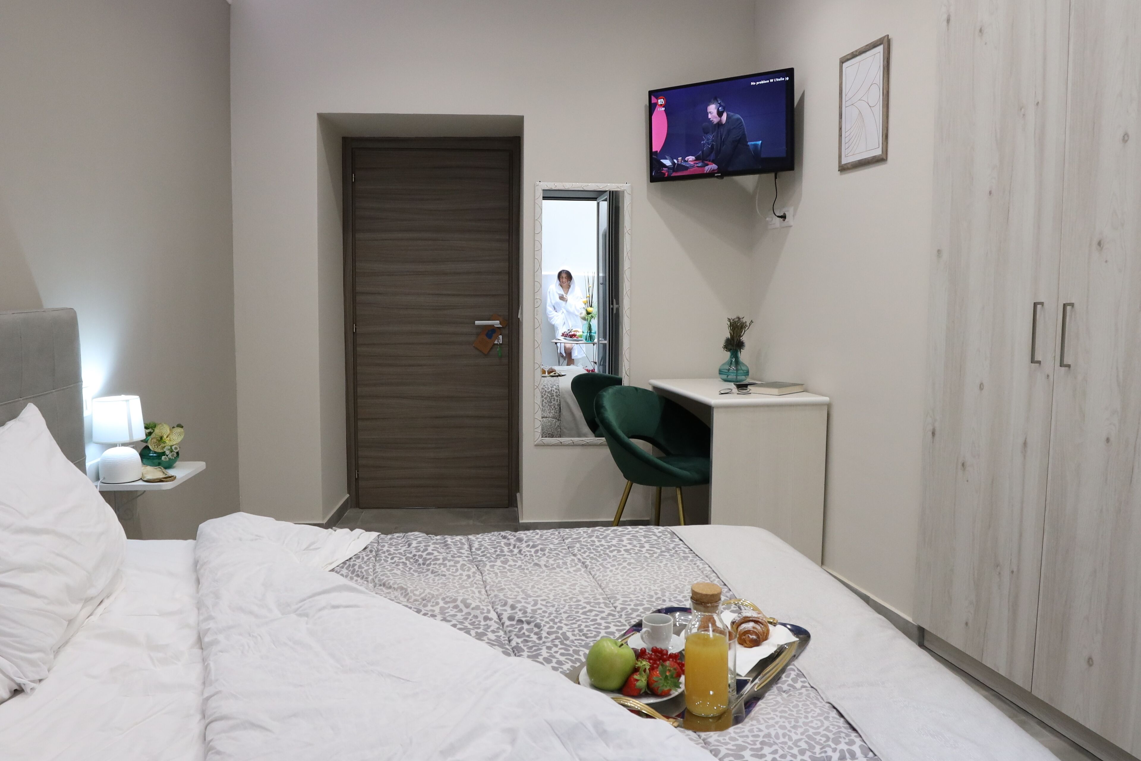 Ein Hotelzimmer mit Bett, Schreibtisch, Fernseher und einem Tablett mit Frühstücksangeboten.