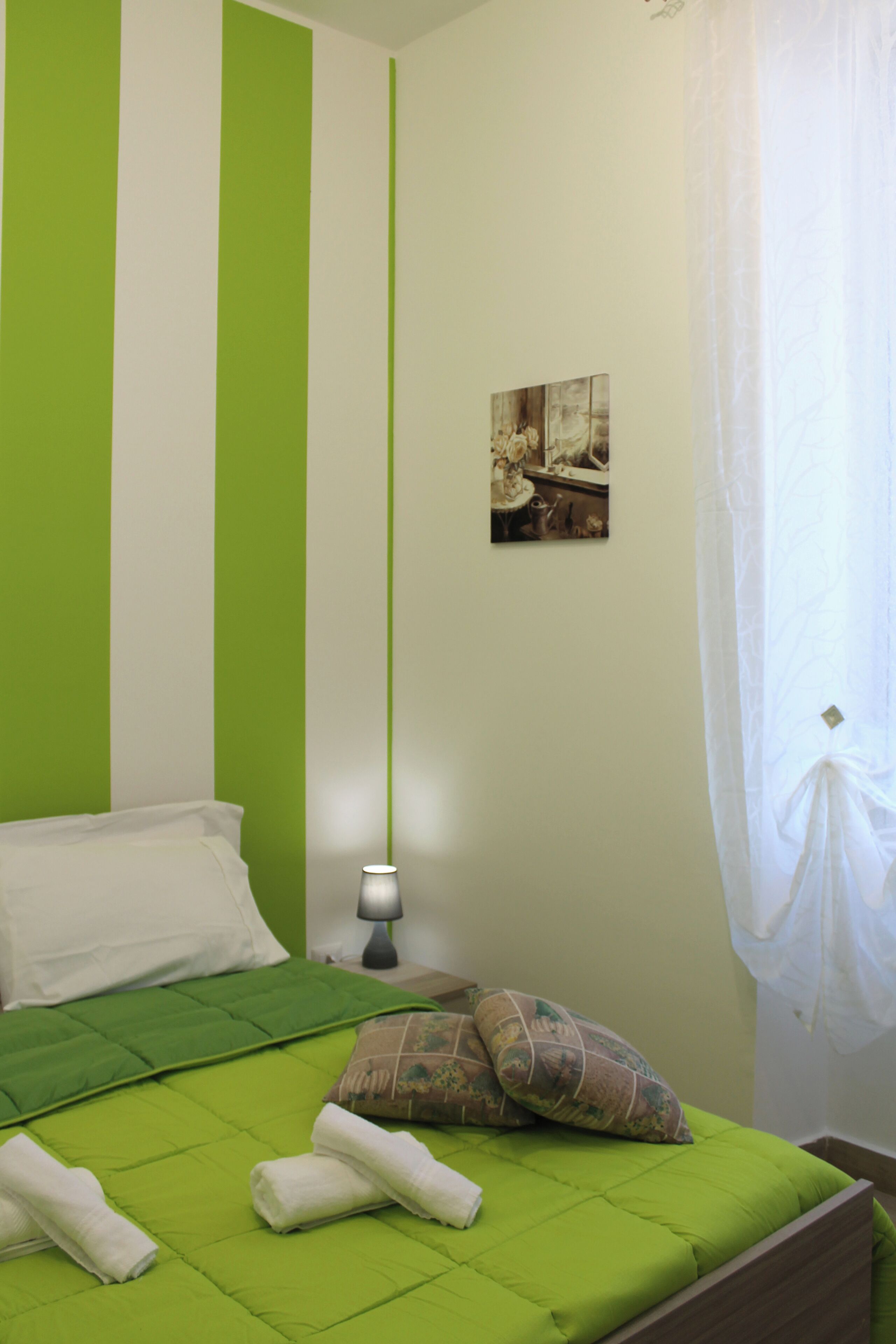 A room with a bed, a nightstand, a lamp, and a painting on the wall.