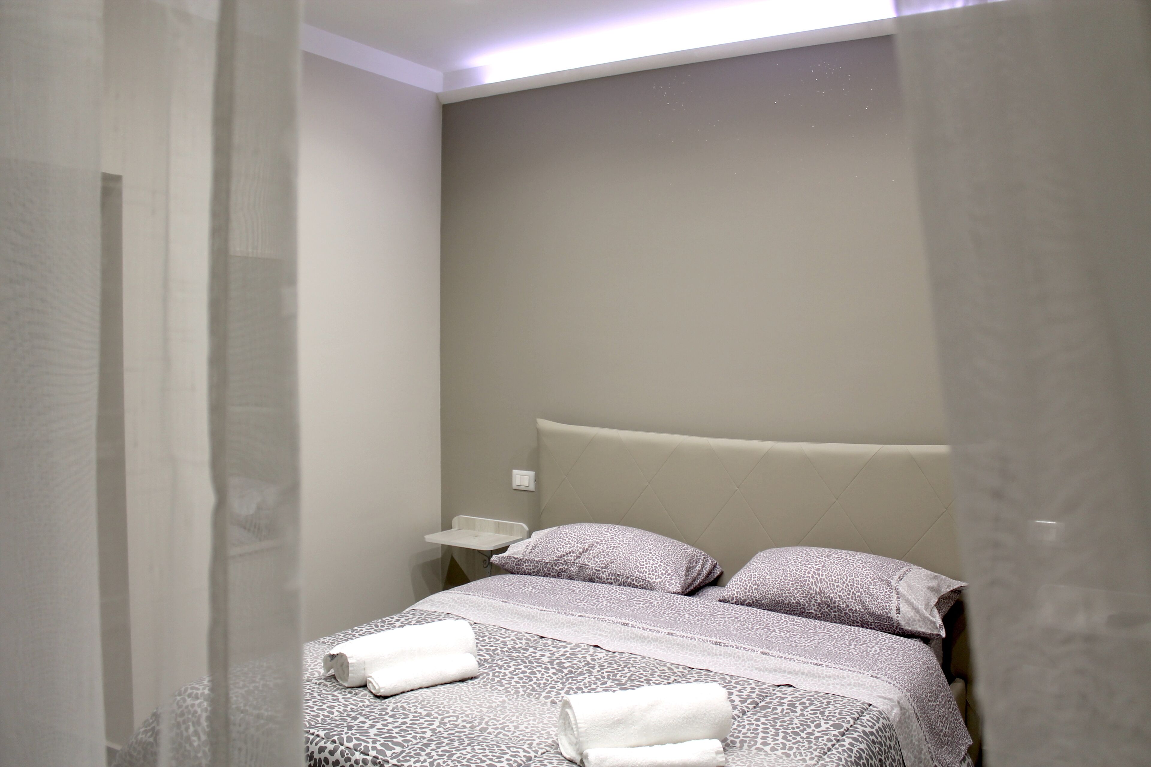 A bedroom with a bed, pillows, and a bedside table.