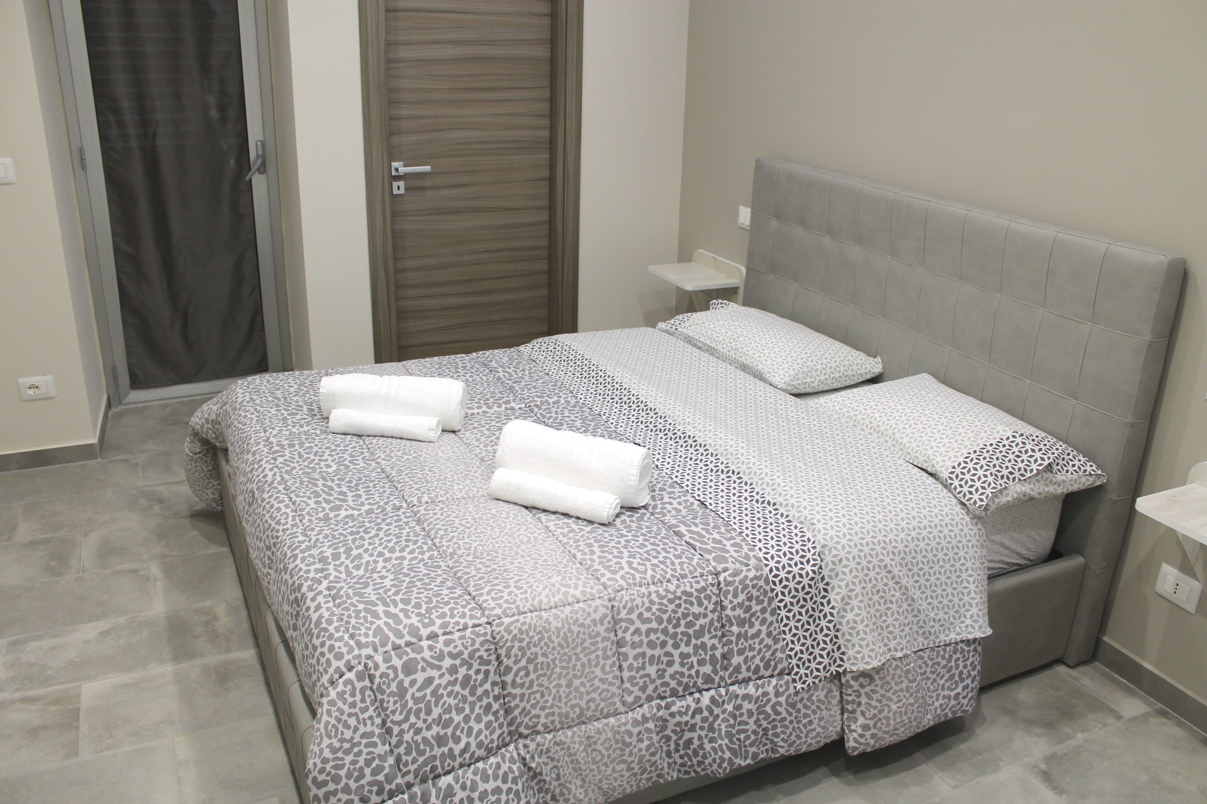 A bedroom with a bed, two bedside tables, and a door.
