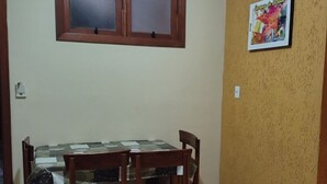 Un comedor con mesa y sillas, una ventana arriba y una pared con un cuadro enmarcado.