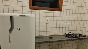 Una cocina con un refrigerador blanco, una estufa a gas y una ventana sobre el fregadero.