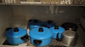 Una cocina con baldosas estampadas, una encimera y estantes con ollas y una caja de té.