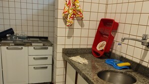 Una cocina con armarios blancos, encimera de granito, un lavabo y un escurreplatos rojo.