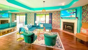 Un salon aux murs de couleur turquoise, doté d’une cheminée et d’un grand téléviseur.