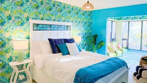 Une chambre à coucher avec un lit, une table de chevet, une lampe, une fenêtre et une vue sur l’extérieur.