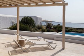 Una terraza en la azotea con sillones blancos, una mesita y vistas al mar.