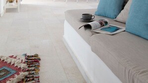 Un salon moderne avec un canapé, une table à manger et des chaises, un luminaire suspendu et un tapis à motifs.