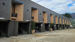 Un immeuble moderne composé de plusieurs logements, chacun étant doté d’une porte à lattes en bois et d’un pot de fleurs placé devant l’entrée.