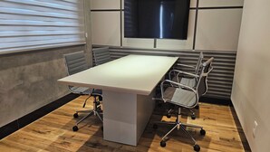 Une salle de conférence équipée d’une grande table, de chaises, d’un téléviseur fixé au mur et d’une fenêtre avec des stores.