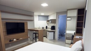 Une chambre d’hôtel moderne dotée d’un grand lit, d’un bureau, d’une kitchenette et d’un téléviseur fixé au mur.