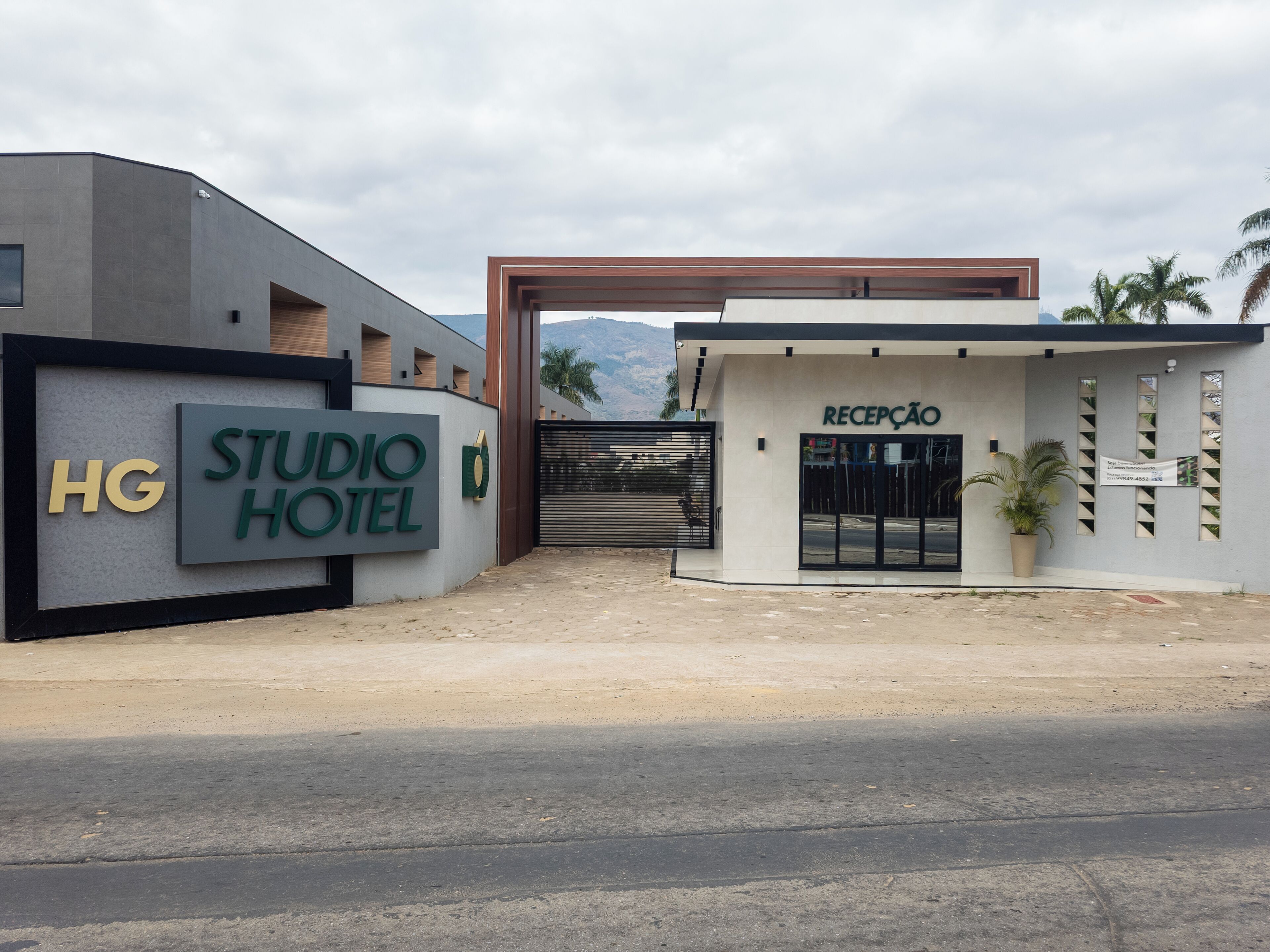 A modern hotel entrance with a reception area, a sign reading "STUDIO HOTEL," and a gate.
