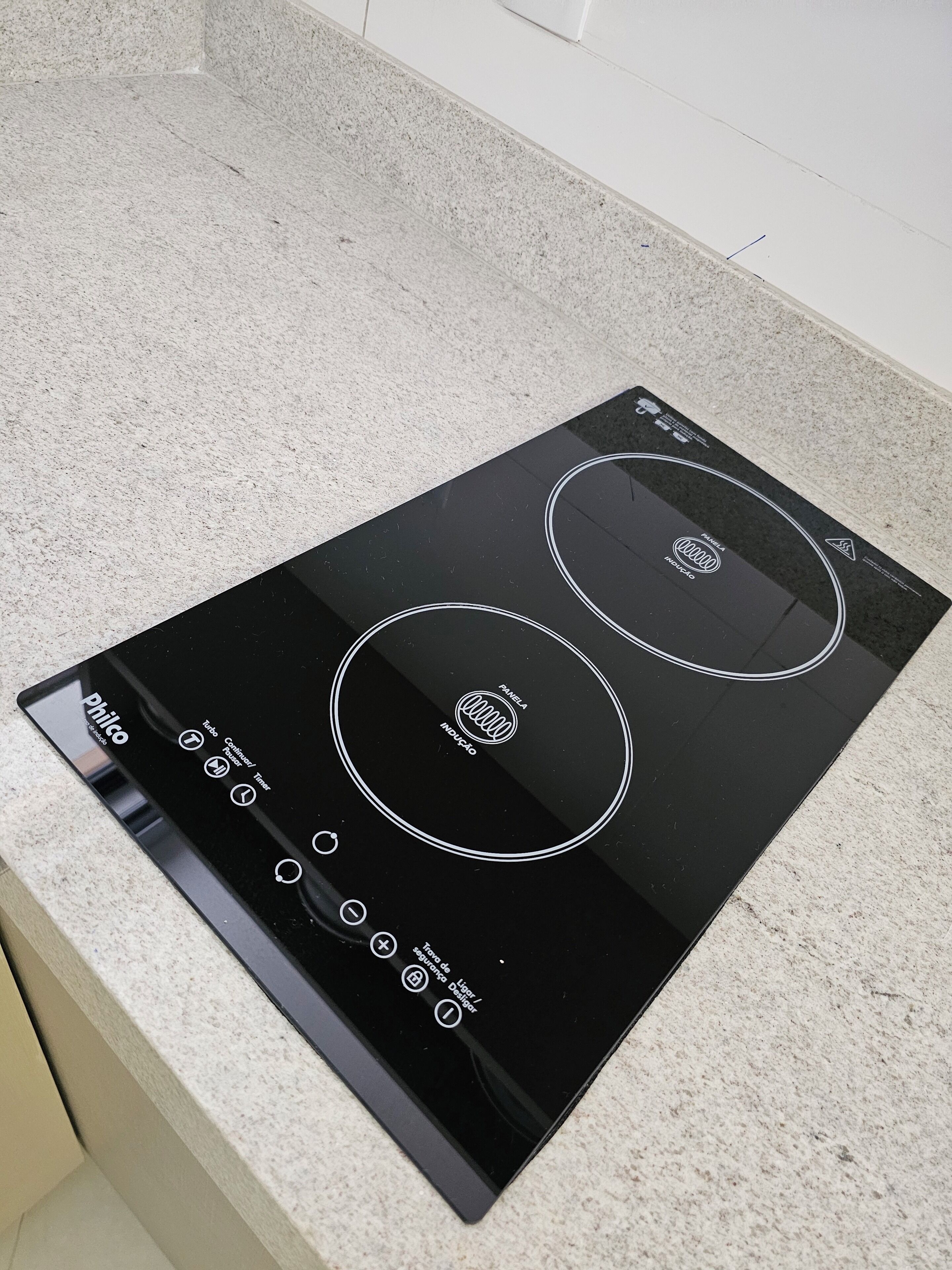 A black induction cooktop with two control panels on a granite countertop.
