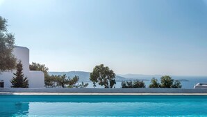 A clear blue pool with a view of white buildings and trees, and distant mountains. - Alluring Mykonos Villa | Villa Kyma | 4 Bedrooms | Panoramic Sea Views |. (Mykonos)