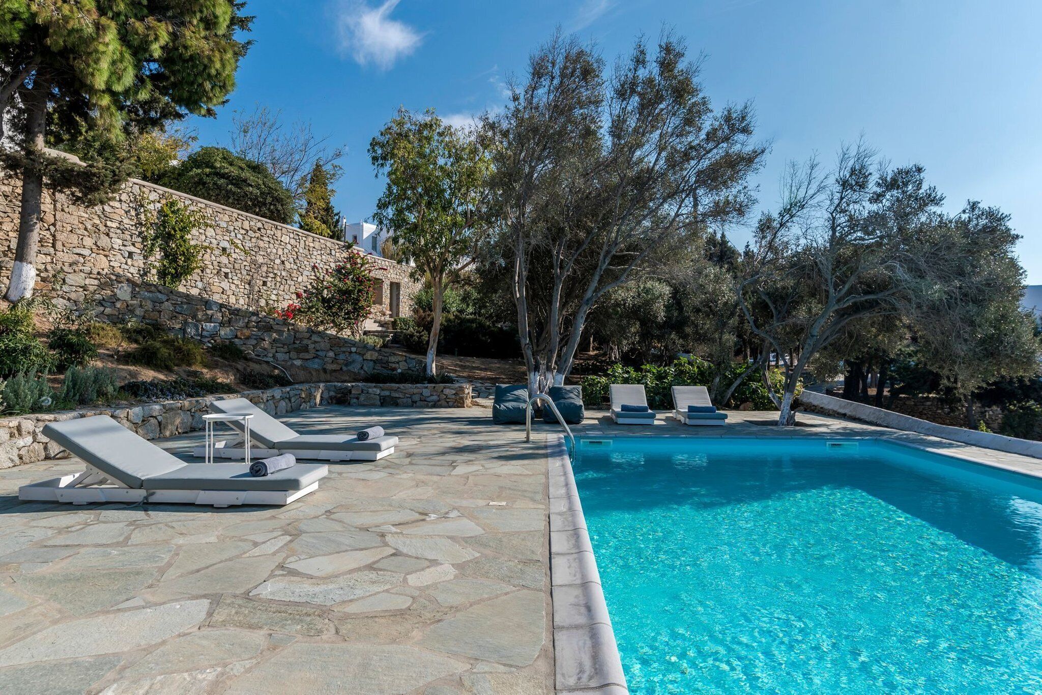 A swimming pool with lounge chairs and a stone wall.