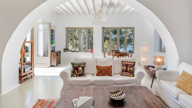 A cozy living room with a white sofa, a wooden coffee table, and a bookshelf. - Alluring Mykonos Villa | Villa Kyma | 4 Bedrooms | Panoramic Sea Views |. (Mykonos)