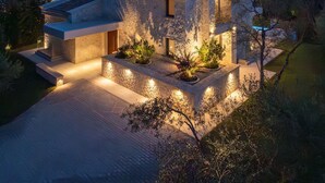 Een modern huis met een stenen gevel, een plat dak en een goed verlichte oprit.