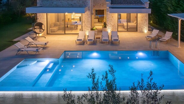 Een modern huis met een zwembad, buiten zitplaatsen en een goed verlicht terras.