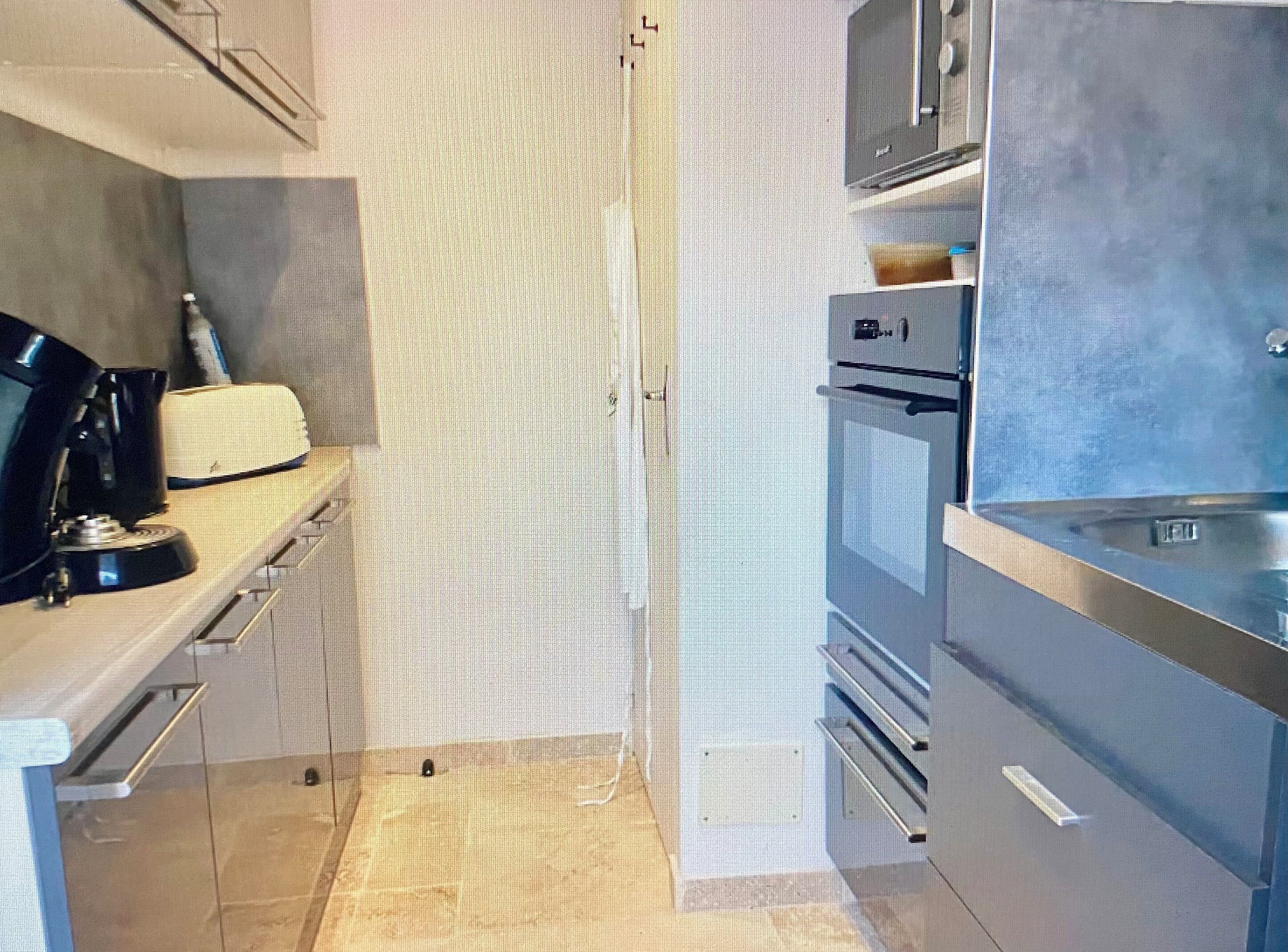 A modern kitchen with stainless steel appliances, a built-in oven, and a coffee maker.