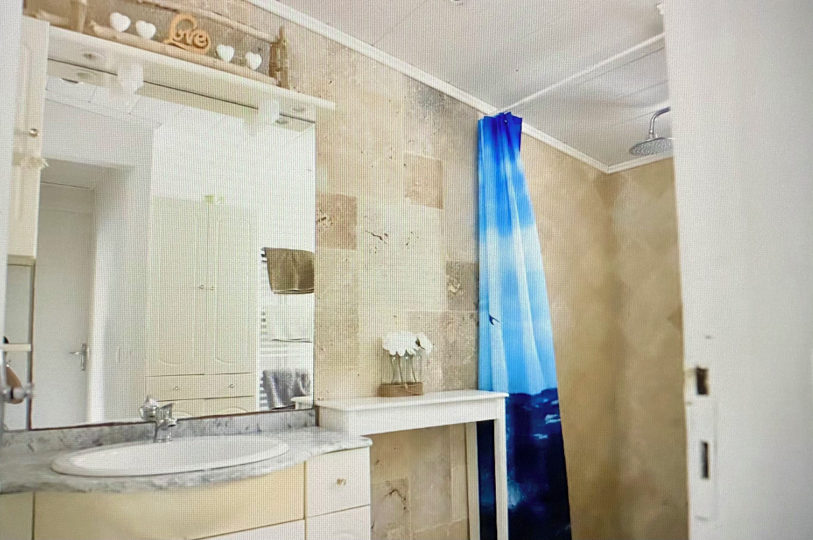 Un bagno con uno specchio grande, un lavandino e una doccia con tenda blu.