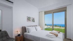 Een slaapkamer met een bed, een stoel en uitzicht op zee.