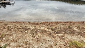 Un lago con un muelle y una orilla arenosa.