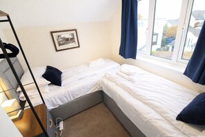 A small, well-lit room with two single beds, a bunk bed, a framed picture on the wall, and a window with curtains. - Molly's Mews, Bowness on Windermere, with lake view (Bowness on Windermere)