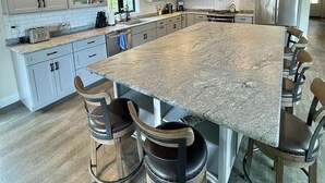 Een ruime keuken met een groot eiland, barkrukken en moderne apparaten.