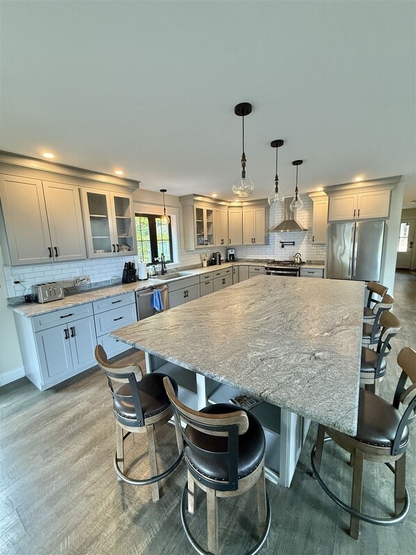 A spacious kitchen with a large island, bar stools, and modern appliances. - Waterfront home has 3-bedroom 3 bath (Sebago)