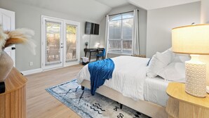 Une chambre à coucher avec un lit, un bureau, une chaise, un téléviseur et un ventilateur de plafond.