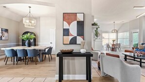 Un vaste espace de vie comprenant une table à manger, des chaises et un lustre moderne.
