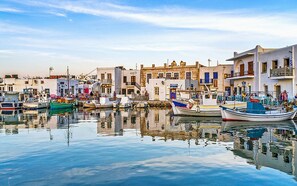 A harbor with boats docked, buildings with balconies, and a calm water surface reflecting the structures. - Wonderful Santorini Room | Olympia Room | Breathtaking Caldera and Sea Views |. (Santorini)