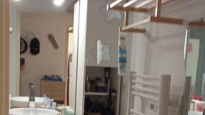 A compact kitchen with a sink, washing machine, and drying rack.
