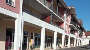 A multi-story building with a row of shops on the ground floor.
