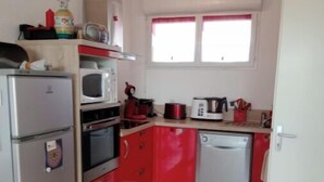 A compact kitchen with a refrigerator, microwave, oven, and a small dishwasher.