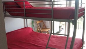 A bunk bed room with red bedding and a painting on the wall.