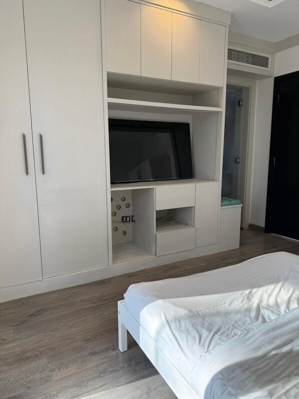 Un dormitorio con cama, televisor y armario.