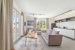 Ein modernes Wohnzimmer mit Sofa, Couchtisch und Küchenzeile mit Schränken und einer Mikrowelle.