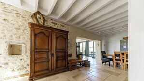 A spacious room with a large wooden wardrobe, a bench, and a dining area with a table and chairs. - Gîte de charme à la campagne Charroux (Charroux)