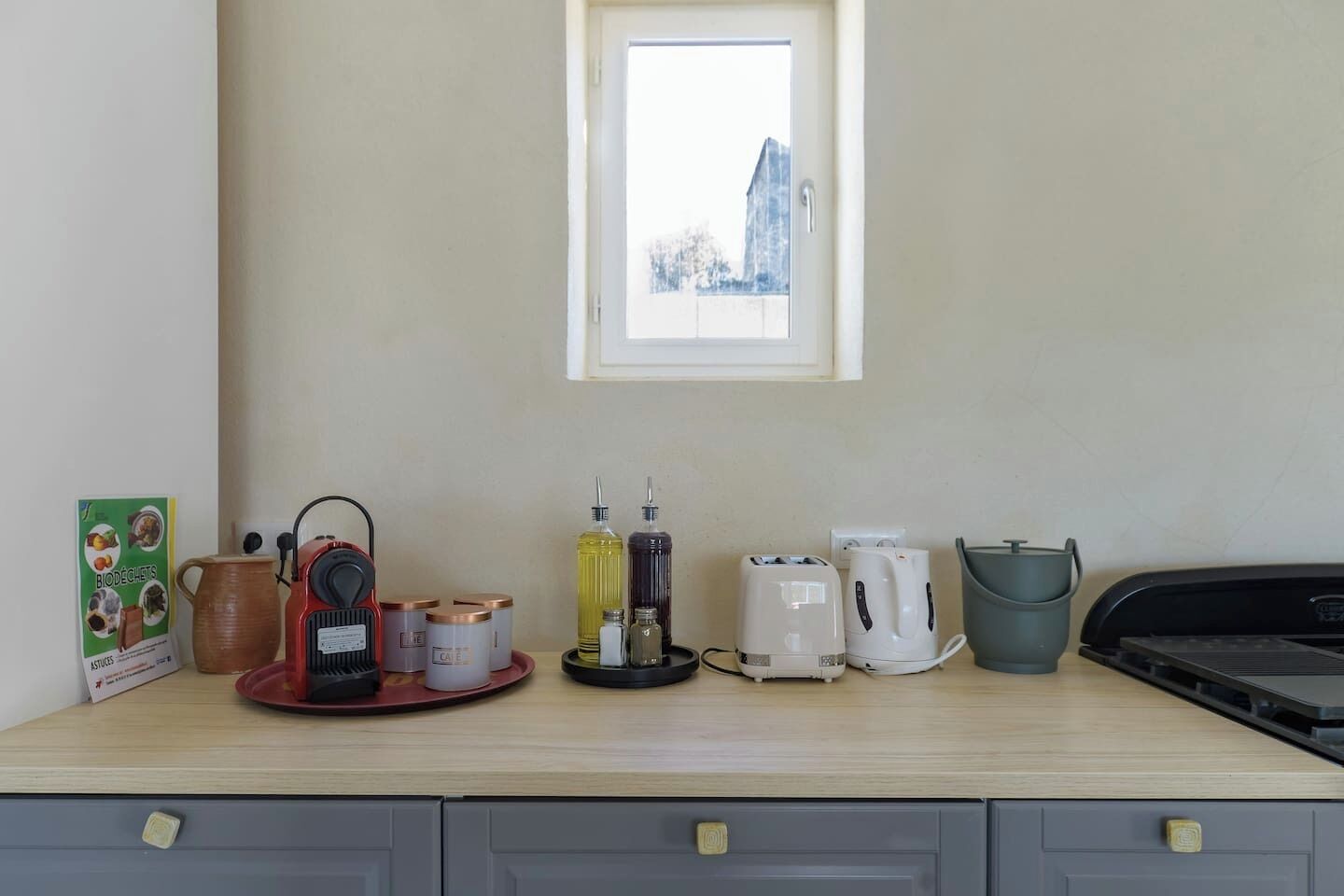 A kitchenette with a coffee maker, toaster, kettle, and a small window above the counter.