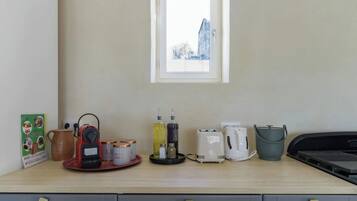 A kitchenette with a coffee maker, toaster, kettle, and a small window above the counter.