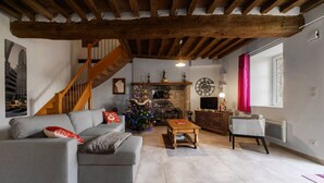 A living room with a grey sofa, a wooden coffee table, a staircase, a decorated Christmas tree, and a fireplace. - Gîte de caractère Charroux La Samandre (Charroux)