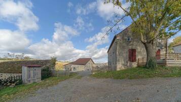 A rural property with a stone barn, a wooden fence, and a gravel driveway.