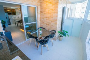 Ein Balkon mit Tisch und Stühlen, einem Blumentopf und Blick auf die angrenzende Küche.