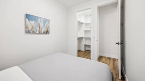 A bedroom with a bed, a closet, and a painting on the wall.