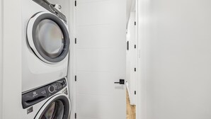 A laundry room with two front-loading washing machines and a dryer.