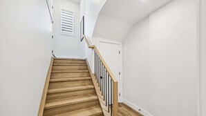 A wooden staircase with black railings leading to a white door.